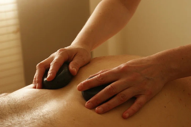 Spa body treatment setting with stones, towels, and eucalyptus accents